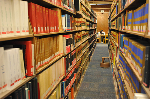 Image of book shelves, with a studying student in the background