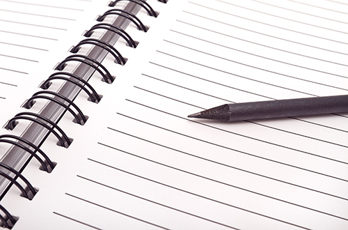 A close up image of a blank notebook and pencil