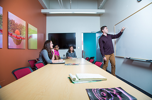 Image of a small group tutoring session, with tutor writing on the white board