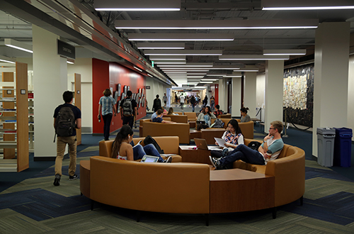 Image of UCSB Library hallway, with students walking by and sitting down on couches